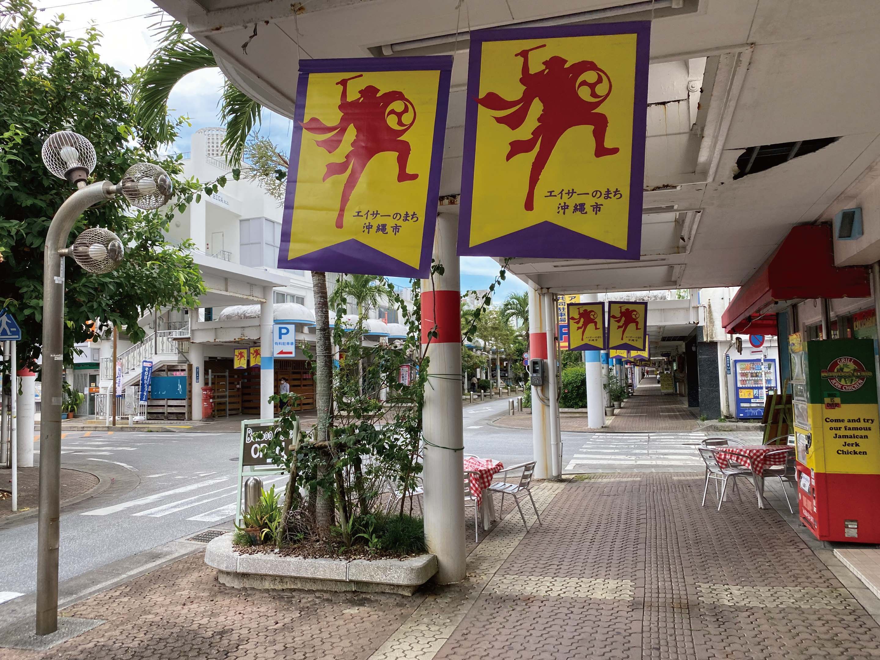 A street with a pedestrian crossing, a parking sign, and a restaurant with outdoor seating.