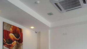 A reception desk with a modern design, a black chair, and a painting of flowers on the wall. - Indah Garden Hotel (Ampang)