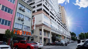 A hotel with multiple floors, a visible sign for the hotel, and several parked cars along the street. - Indah Garden Hotel (Ampang)