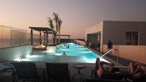 Un área de piscina en la azotea con sillones de descanso y una bañera de hidromasaje.