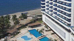A high-rise hotel with multiple balconies overlooking a beach and a pool area. - Condominio Reserva del Mar, Apto Estilo Resort, Salida Privada a la Playa (Santa Marta)