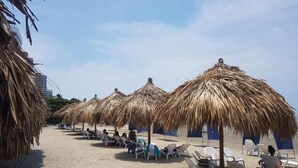 A beach with thatched umbrellas and white lounge chairs. - Condominio Reserva del Mar, Apto Estilo Resort, Salida Privada a la Playa (Santa Marta)