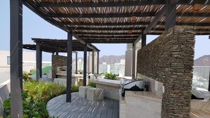 An outdoor patio with a stone wall, wooden deck, and a pergola. - Condominio Reserva del Mar, Apto Estilo Resort, Salida Privada a la Playa (Santa Marta)
