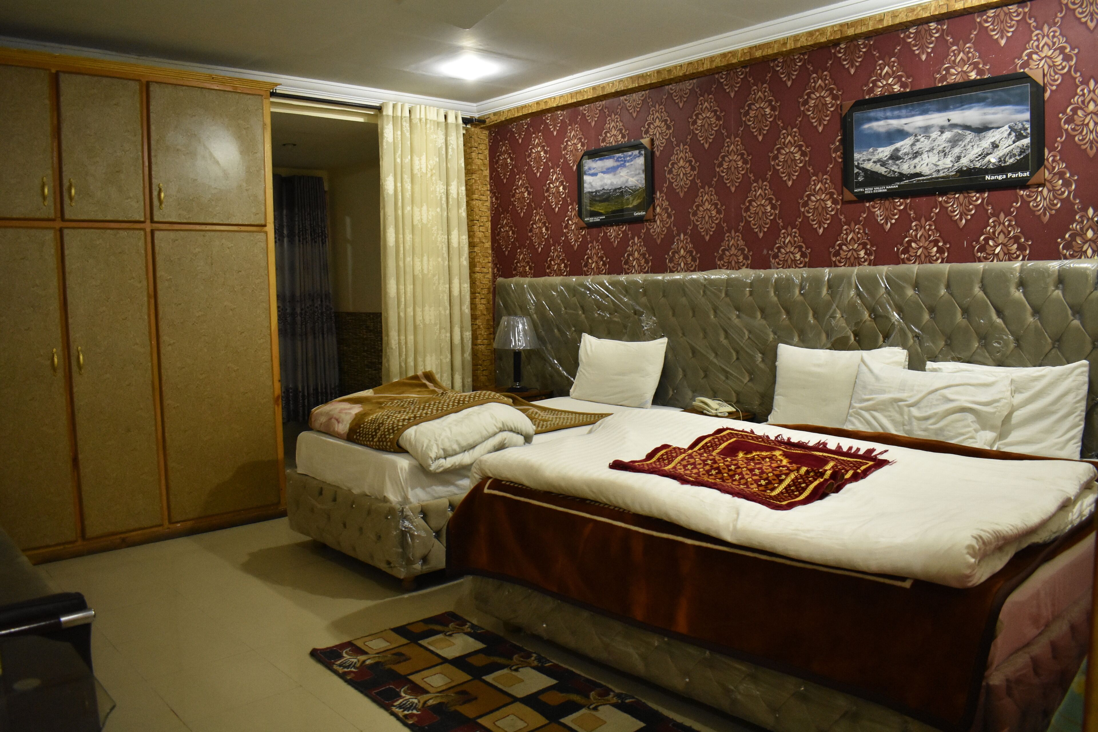 A hotel room with a large bed, a wardrobe, and a television on the wall.