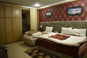 A hotel room with a large bed, a wardrobe, and a television on the wall. - Rose Valley Hotel (Balakot)