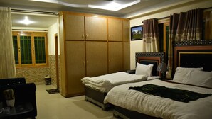 A hotel room with two beds, a wardrobe, a dining area with a table and chairs, and a window with curtains. - Rose Valley Hotel (Balakot)