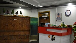 A reception area with a wooden reception desk, a green door, and a wall-mounted sign indicating a kitchen. - Rose Valley Hotel (Balakot)