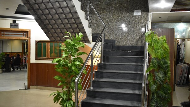 A staircase with a metal railing, a potted plant, and a sign indicating a restaurant. - Rose Valley Hotel (Balakot)