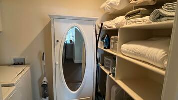 A compact laundry room with a washing machine, dryer, and a mirror cabinet.