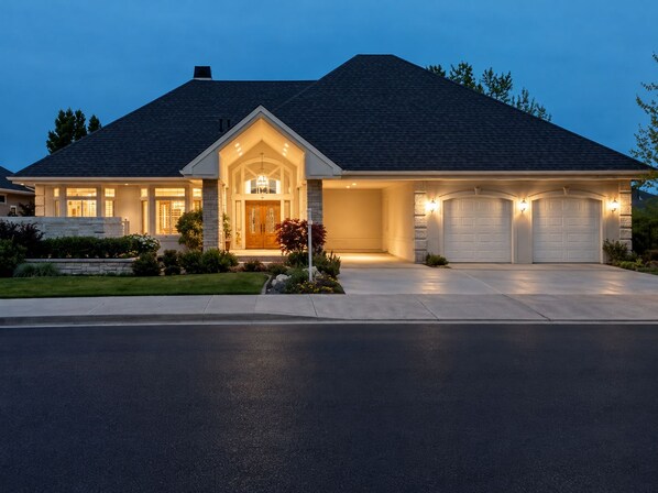 A two-story house with a front porch, a garage with two doors, and a well-maintained lawn.
