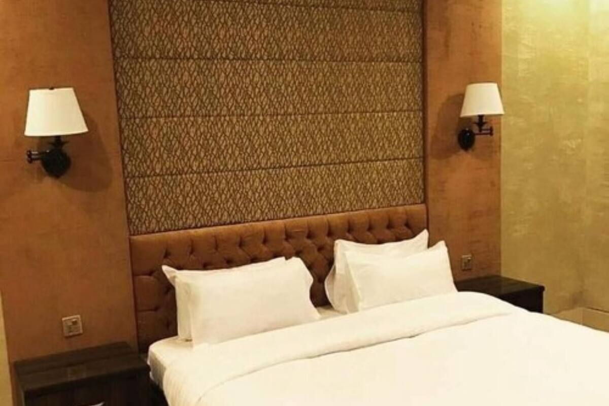 Een keurig opgemaakt bed met witte lakens in een hotelkamer.
