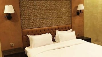 A neatly made bed with white linens in a hotel room.