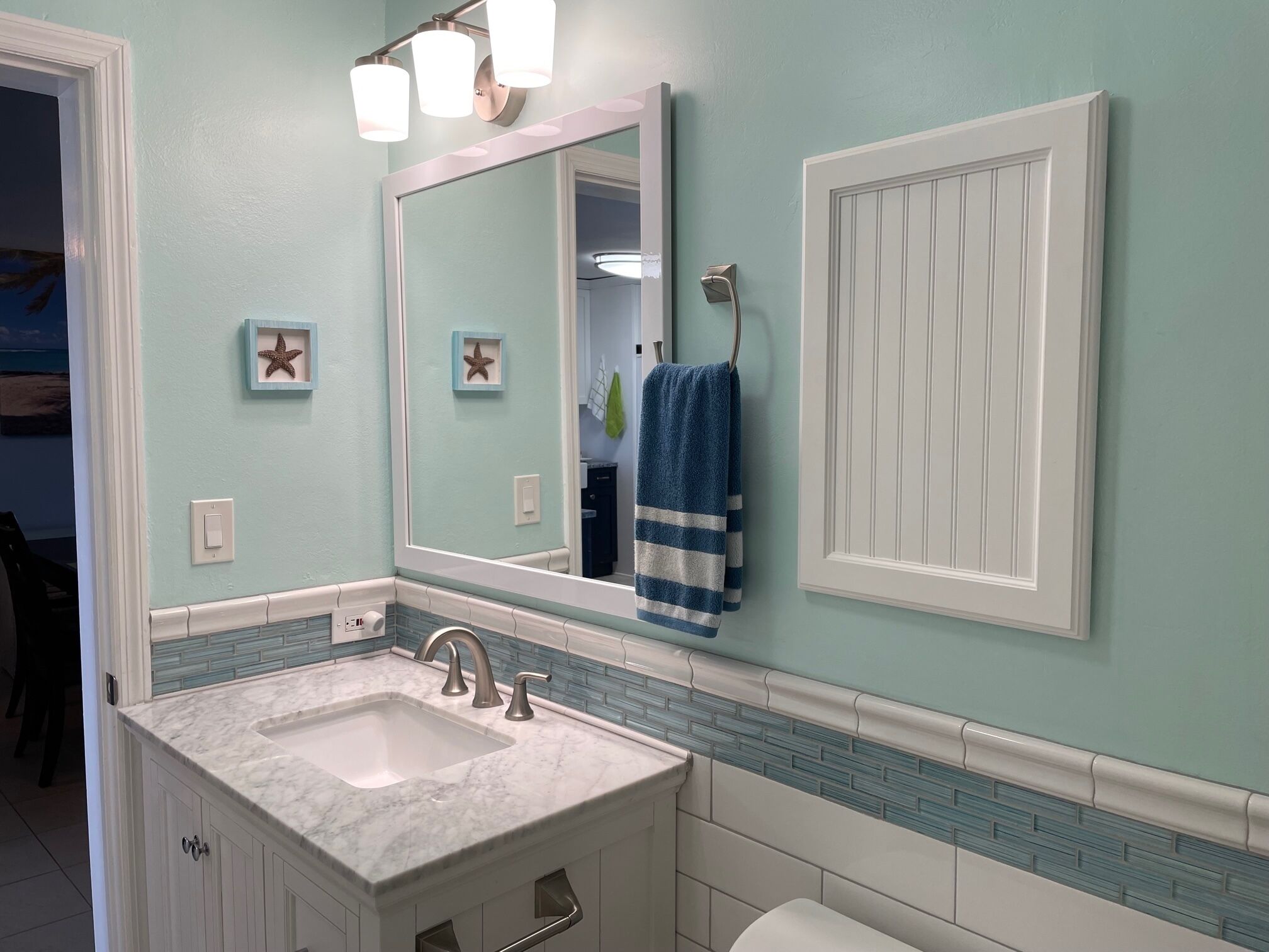 A bathroom with a marble sink, a large mirror, and a towel rack.