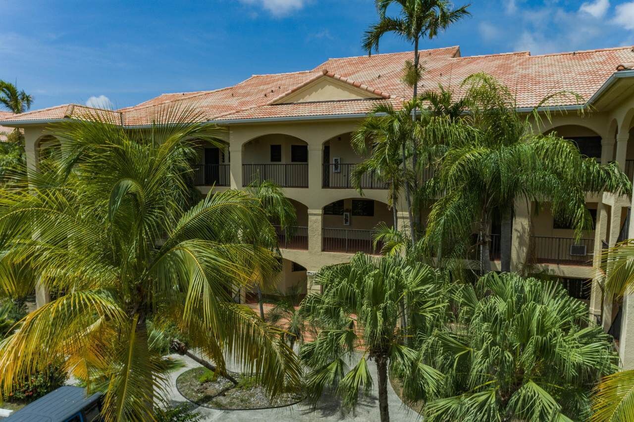 A hotel with a tiled roof, multiple balconies, and lush palm trees.