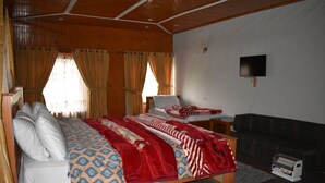 Quarto com cama, televisão, sofá e uma pequena mesa.