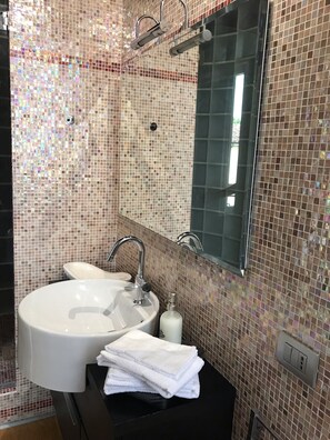 Bathroom features a large round sink, single faucet, and a rectangular mirror with a dark frame.
