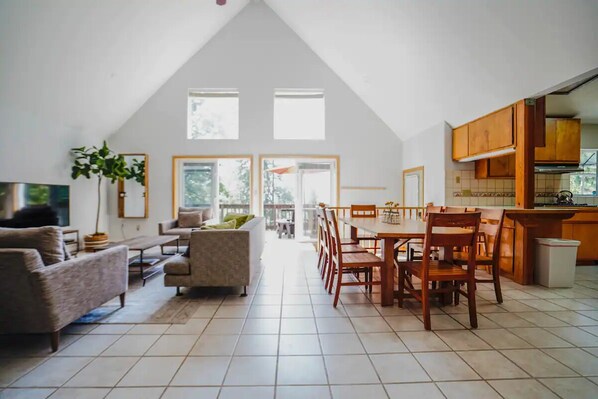 A spacious living area with a dining table and chairs, a sofa, and a TV. - Family Mountain Retreat Near Pinecrest W/ Game Room (Cold Springs)