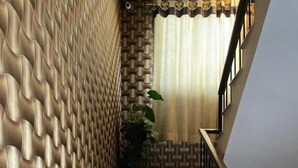 A staircase with a textured wall on one side and a wooden railing on the other. - Hotel Executive Lodge (Karachi)
