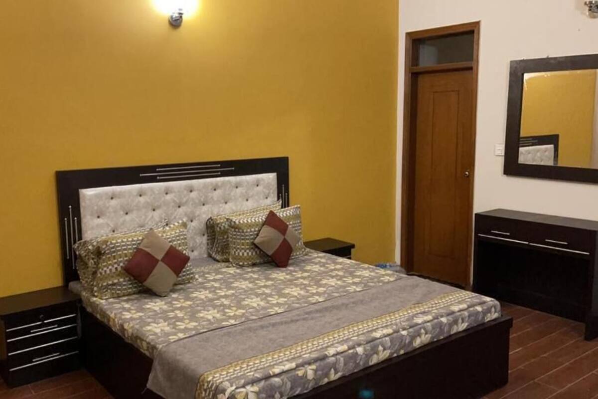 A bedroom with a bed, nightstands, a dresser, a mirror, and a door.