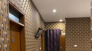 A hotel corridor with patterned walls, a wooden door, and a tiled floor. - Hotel Executive Lodge (Karachi)