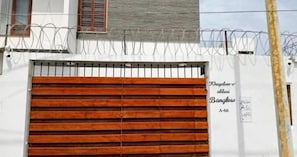A gated entrance with a wooden gate and a sign indicating 'Khayaban-e-abbasi Banglow A-66'. - Hotel Executive Lodge (Karachi)