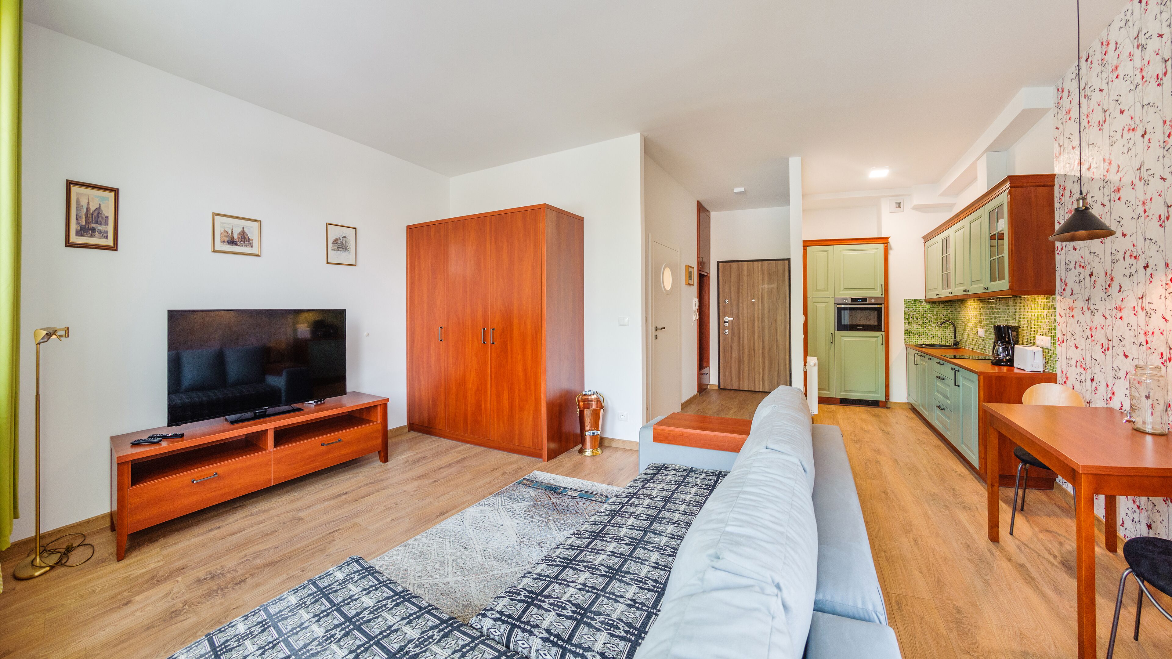 A modern living room with a flat-screen TV, wooden entertainment unit, and a patterned rug.