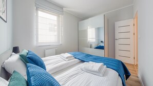 Een slaapkamer met twee bedden, een grote spiegel, een kledingkast en een raam met jaloezieën.