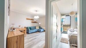 Een moderne woonkamer met een blauwe bank, een houten eettafel en een glazen vaas met bloemen.