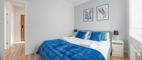 Une chambre à coucher comprenant un lit, des tables de chevet, une porte et deux œuvres d’art accrochées au mur.
