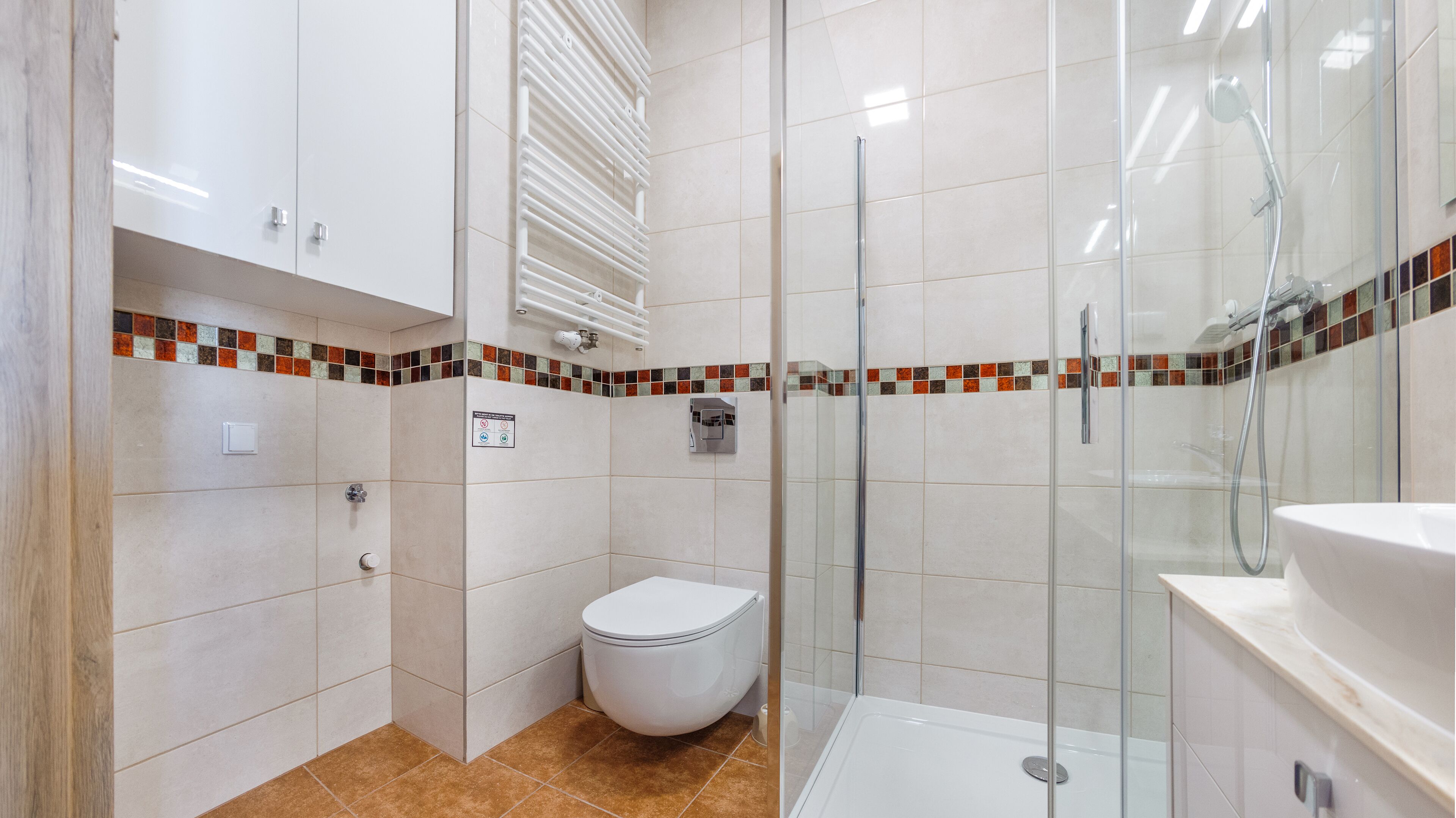 Un baño moderno con cabina de ducha de vidrio, inodoro blanco y lavamanos.