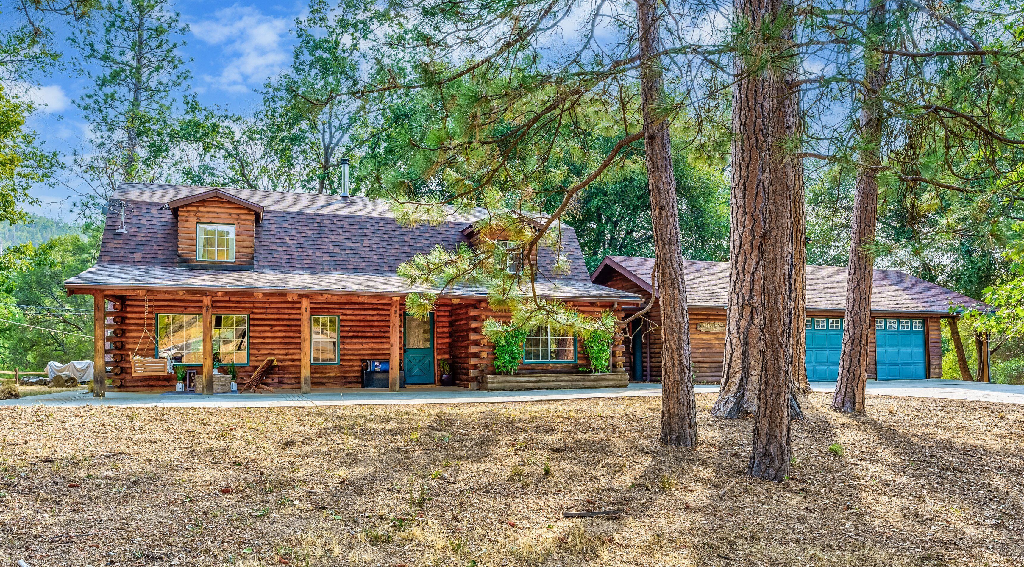 A log cabin with a porch, a garage, and a chimney.