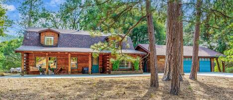 A log cabin with a porch, a garage, and a chimney.
