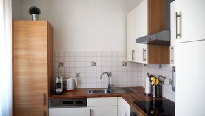 A modern kitchen with wooden cabinets, a dishwasher, a stove, and a sink. - Anastacia Premium Apartment (Graz)