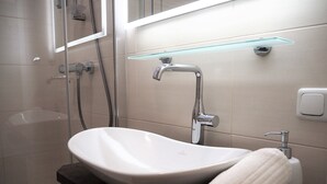 A modern bathroom with a white sink, a glass shower enclosure, and a towel on the counter. - Anastacia Premium Apartment (Graz)