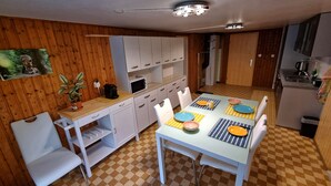 A compact kitchen with a dining area, featuring a microwave, coffee maker, and a sink. - Chez Rosalie (La Roche FR)