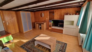A room with wooden walls, a TV, a desk, and a wardrobe. - Chez Rosalie (La Roche FR)