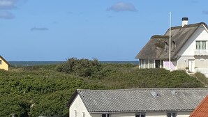 Una casa costera con techo inclinado, balcón y vista al mar.