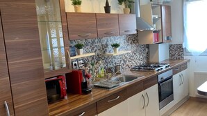 Eine moderne Küche mit Holzschränken, einer gefliesten Spritzschutzwand, einem Herd und einem Spülbecken.