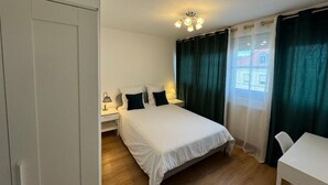 Ein Schlafzimmer mit Bett, Nachttischen, einem Schreibtisch und Vorhängen.