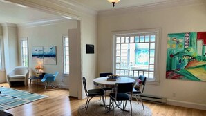 Un comedor con una mesa redonda, sillas y una alfombra. Hay una ventana con vistas al exterior.