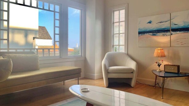 Una sala de estar moderna con un sofá, un sillón y una mesita de noche con una lámpara.