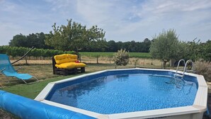 An outdoor swimming pool with a wooden deck, a yellow lounge chair, and a blue lounge chair. - Gîte les trois pierres (Riocaud)