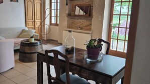 A dining area with a wooden table, chairs, a vase, and a potted plant. - Gîte les trois pierres (Riocaud)