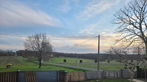 A rural landscape with a gravel path, a wooden fence, and a gate leading to a field. - Gîte les trois pierres (Riocaud)