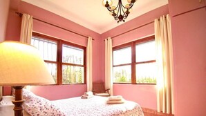 A bedroom with a bed, a lamp, and large windows. - The Cliffs - The Area Nightfall (Viveiro)