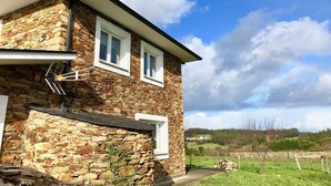 A stone house with a garage, two windows, and a clear sky.
