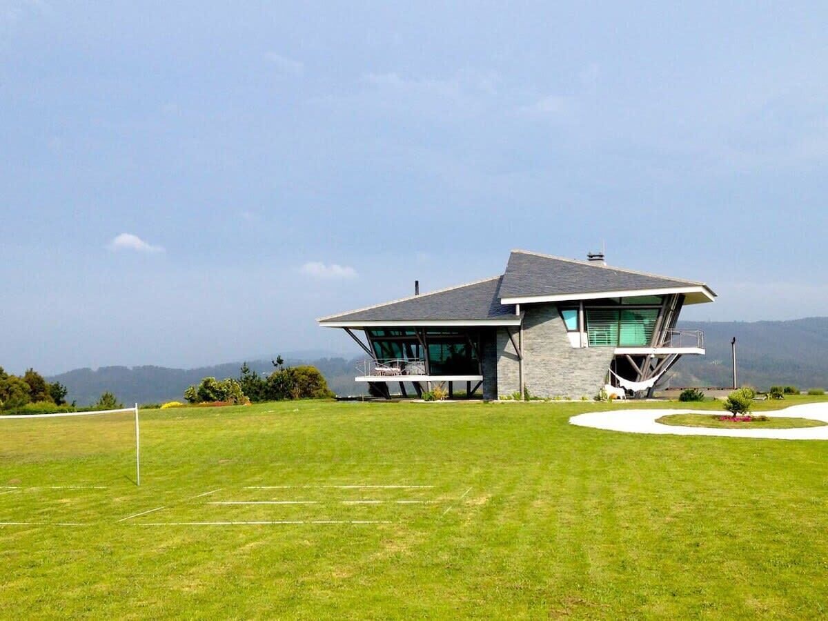 A modern house with a sloped roof, large windows, and a well-maintained lawn.