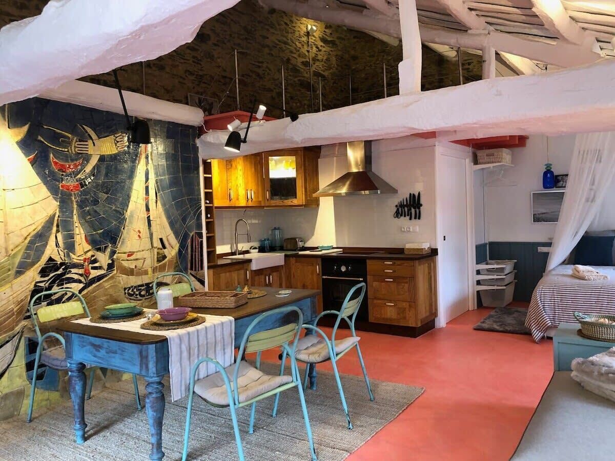 A compact kitchen with wooden cabinets, a central island, and a dining area with a table and chairs.
