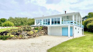 Una casa moderna con un muro de piedra y un balcón azul.