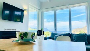 Una sala de estar moderna con un ventanal grande, un televisor de pantalla plana, una mesa de comedor y un sofá.